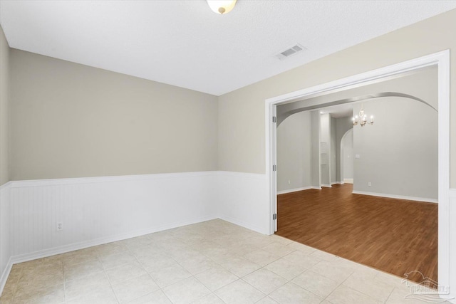 empty room featuring an inviting chandelier and light wood-type flooring