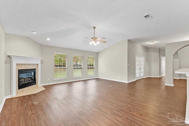 unfurnished living room with dark wood-type flooring, a fireplace, a textured ceiling, and vaulted ceiling