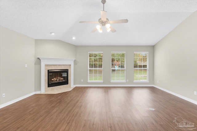 unfurnished living room featuring ceiling fan, hardwood / wood-style floors, a fireplace, a textured ceiling, and vaulted ceiling