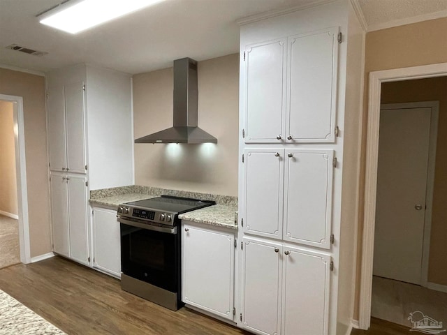 kitchen with hardwood / wood-style flooring, wall chimney exhaust hood, stainless steel electric range, and white cabinetry