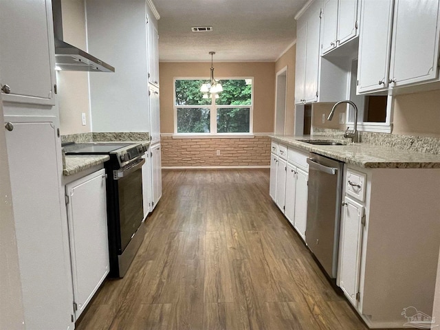 kitchen with pendant lighting, wall chimney range hood, sink, appliances with stainless steel finishes, and white cabinetry