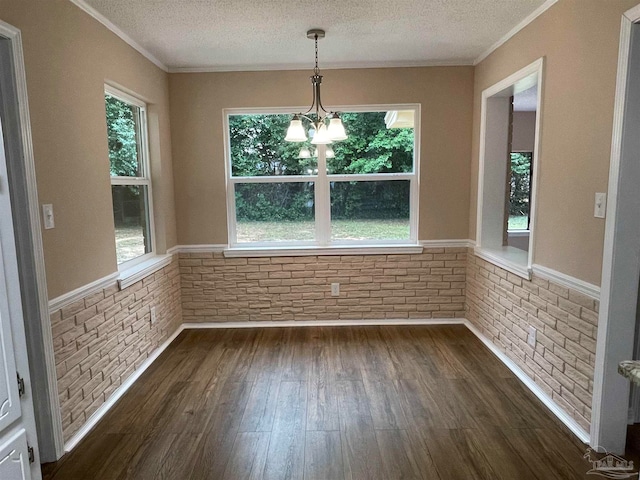 unfurnished dining area with a textured ceiling, ornamental molding, dark hardwood / wood-style floors, and a notable chandelier