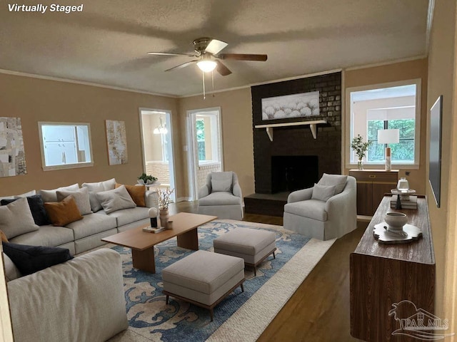 living room featuring a fireplace, crown molding, plenty of natural light, and hardwood / wood-style floors