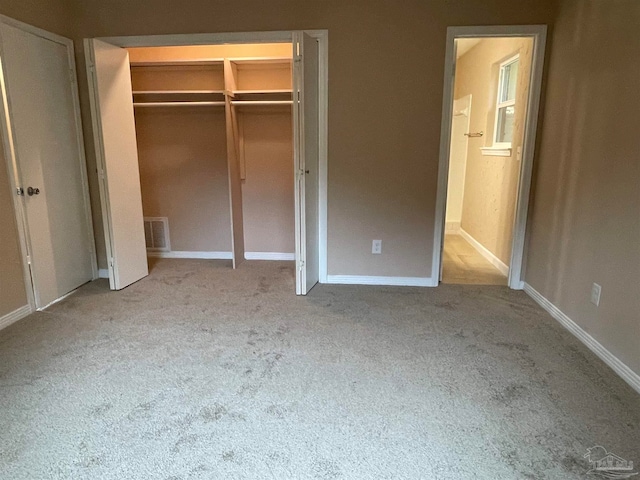 unfurnished bedroom with a closet and light colored carpet