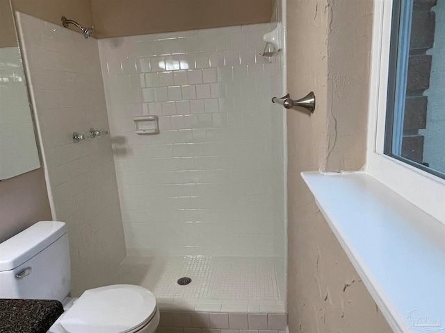 bathroom featuring tiled shower and toilet