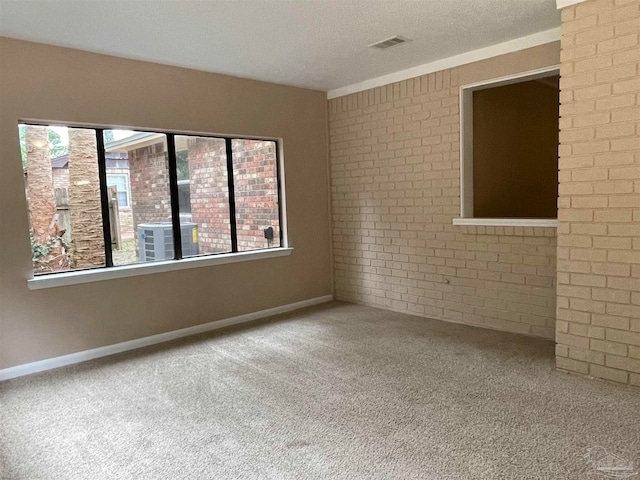 unfurnished room with carpet flooring, a textured ceiling, and brick wall