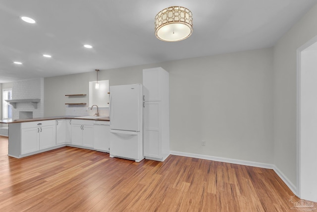 kitchen featuring light wood-style floors, white cabinetry, white appliances, a peninsula, and baseboards