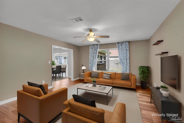 living area featuring light wood-type flooring, baseboards, visible vents, and a ceiling fan