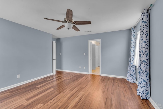 spare room with baseboards, visible vents, ceiling fan, and wood finished floors