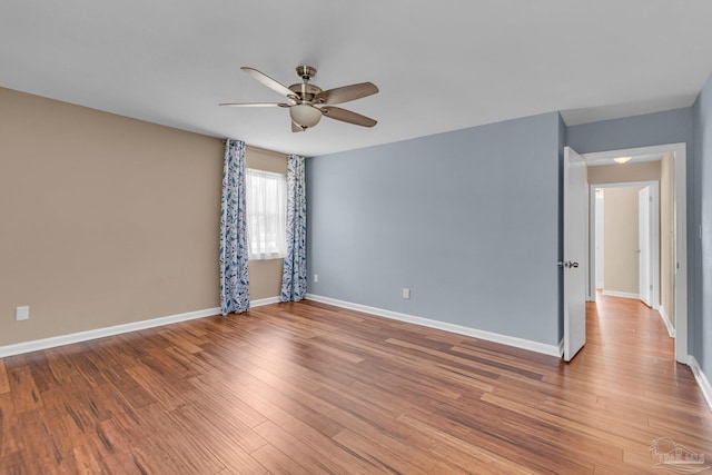 unfurnished room with wood finished floors, a ceiling fan, and baseboards