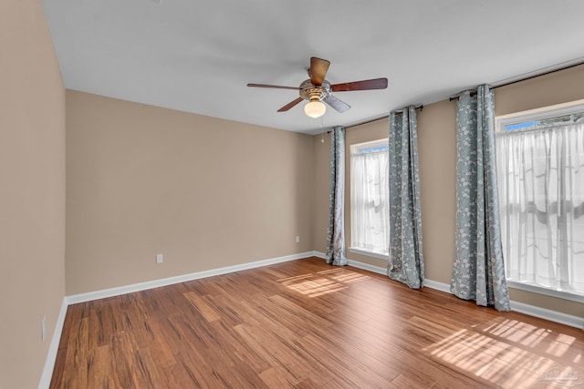 spare room featuring ceiling fan, baseboards, and wood finished floors