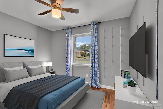 bedroom with ceiling fan, wood finished floors, and baseboards