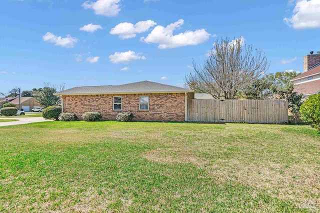 exterior space featuring brick siding, a front lawn, and fence