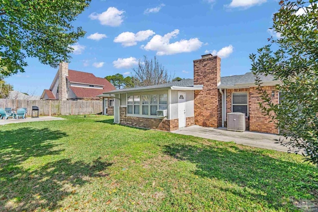 rear view of house featuring brick siding, a patio, a chimney, a lawn, and fence