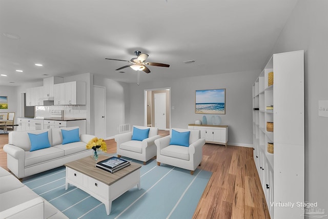 living area featuring light wood-style flooring, visible vents, ceiling fan, and baseboards