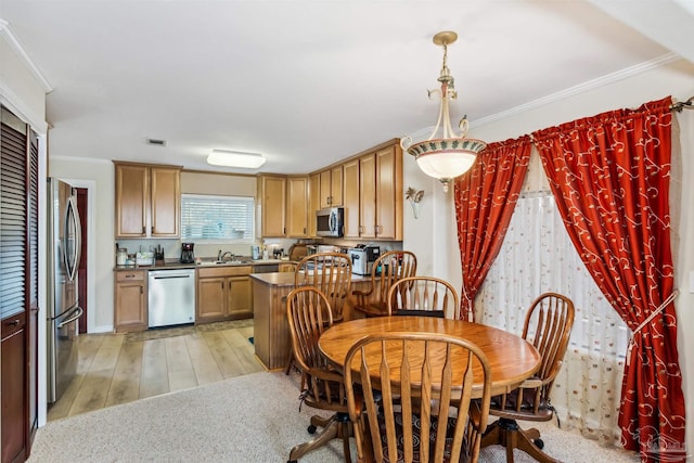 dining room with sink, ornamental molding, and light wood-type flooring