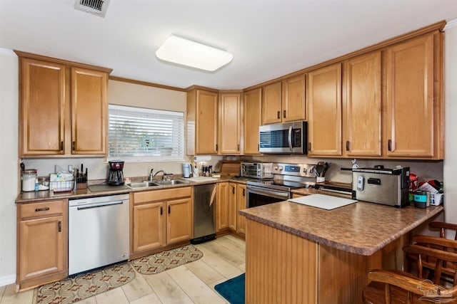 kitchen with appliances with stainless steel finishes, light wood-type flooring, ornamental molding, and sink