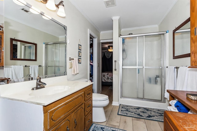 bathroom with hardwood / wood-style floors, vanity, crown molding, toilet, and walk in shower