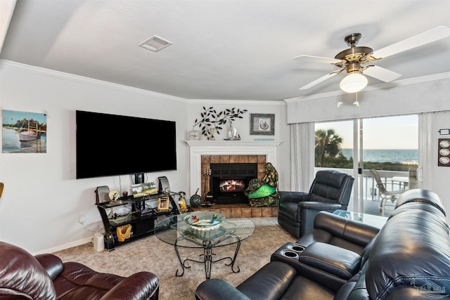 living room with a tiled fireplace, ceiling fan, light carpet, and ornamental molding