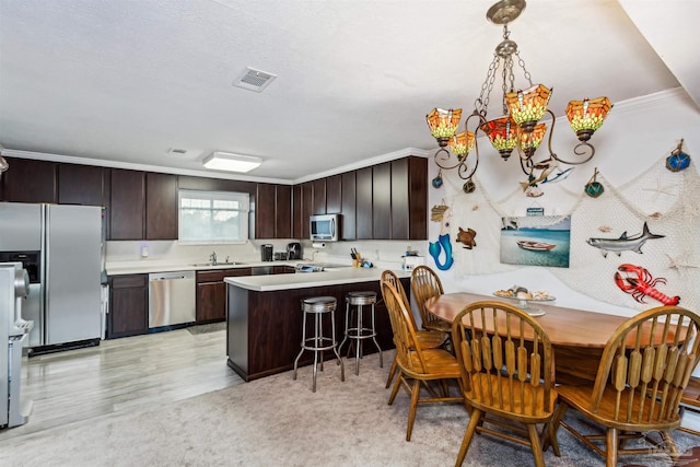 kitchen with light wood-type flooring, appliances with stainless steel finishes, dark brown cabinetry, and kitchen peninsula