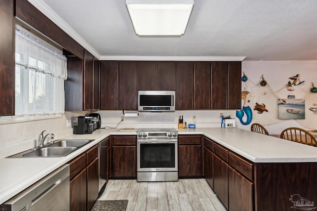 kitchen featuring stainless steel appliances, kitchen peninsula, light wood-type flooring, dark brown cabinets, and ornamental molding