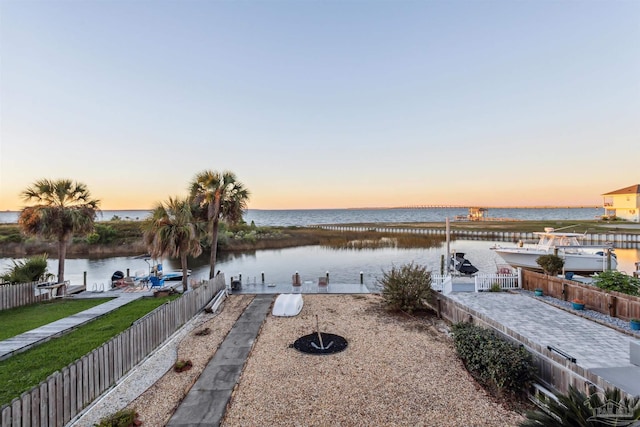 patio terrace at dusk with a water view and a dock