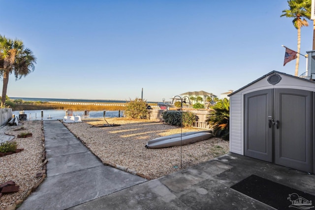 view of yard featuring a storage unit, a patio area, and a water view