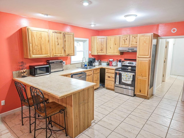 kitchen with under cabinet range hood, a kitchen bar, appliances with stainless steel finishes, a peninsula, and a sink