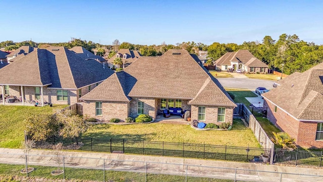 view of front of house featuring a shingled roof, a fenced backyard, brick siding, and a front lawn