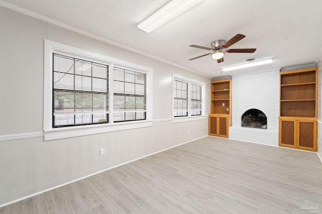 unfurnished living room featuring crown molding, a fireplace, light wood-style flooring, ceiling fan, and a textured ceiling