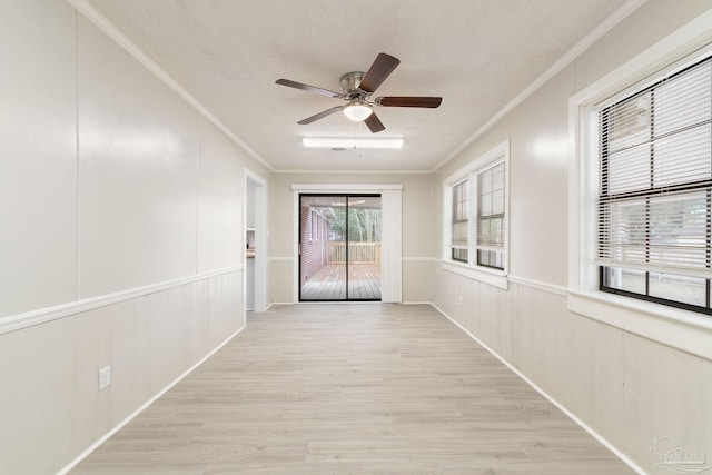 empty room with light wood-style floors, a decorative wall, and crown molding