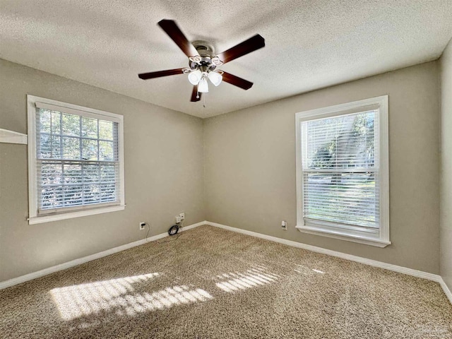 carpeted spare room with plenty of natural light, baseboards, and ceiling fan