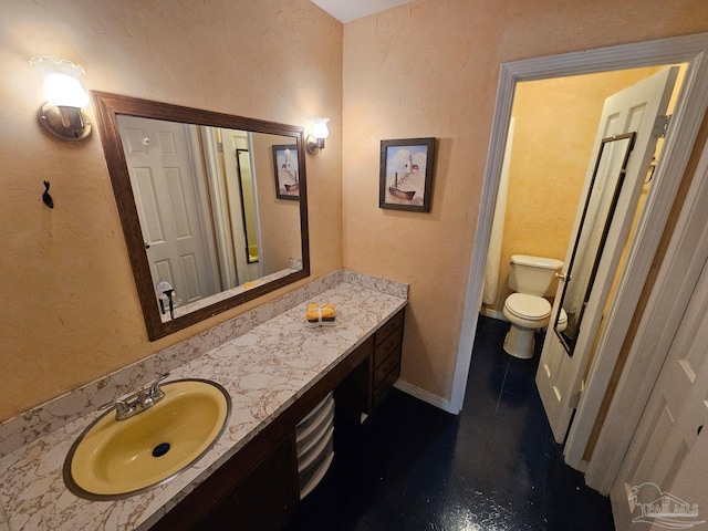 bathroom with toilet, baseboards, and vanity