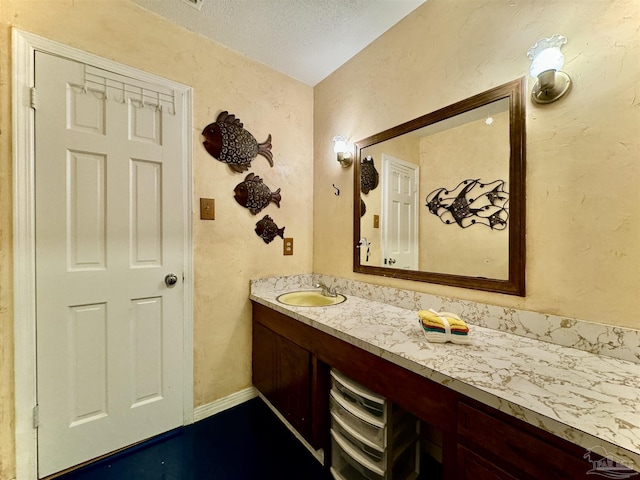 bathroom featuring baseboards, a textured ceiling, and vanity