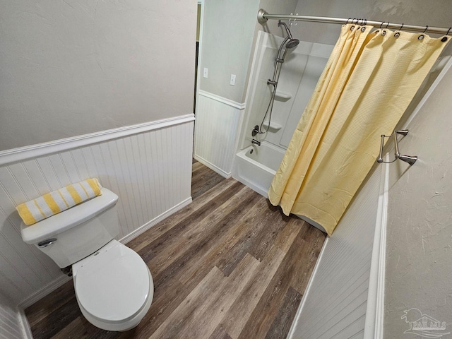 full bath with toilet, shower / bath combination with curtain, wood finished floors, and wainscoting