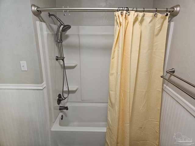 bathroom with shower / tub combo and a wainscoted wall