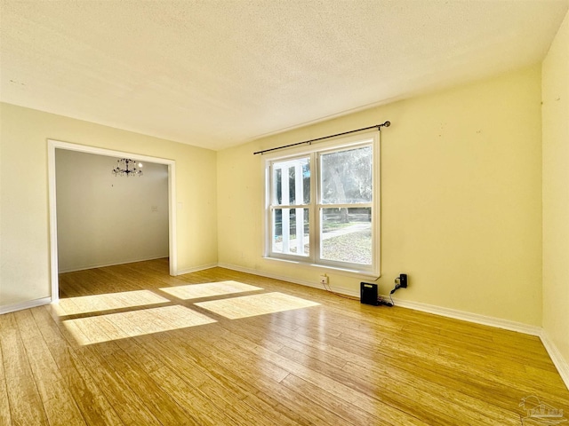 empty room featuring baseboards, a textured ceiling, and hardwood / wood-style floors