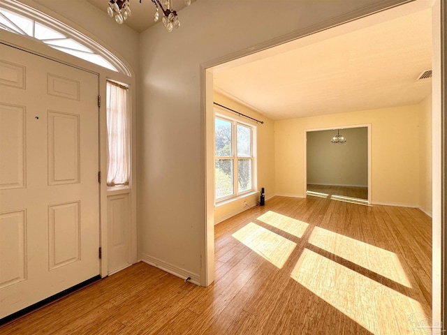 entrance foyer featuring a chandelier, visible vents, baseboards, and wood finished floors