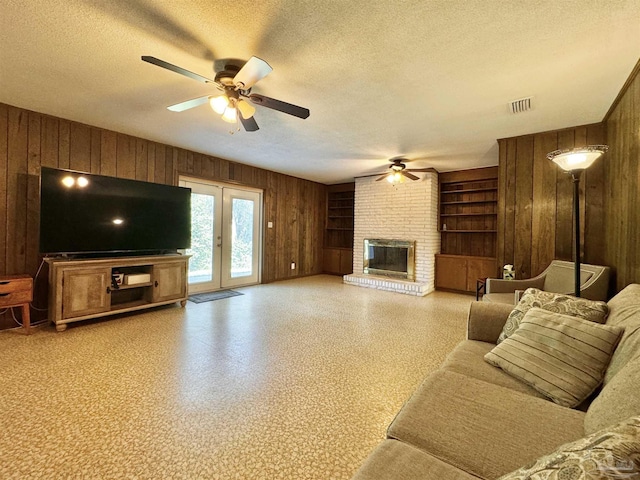 living area featuring a textured ceiling, wood walls, and a fireplace