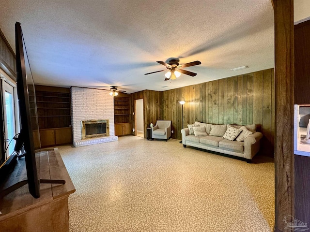 unfurnished living room featuring a textured ceiling, a fireplace, visible vents, and wooden walls