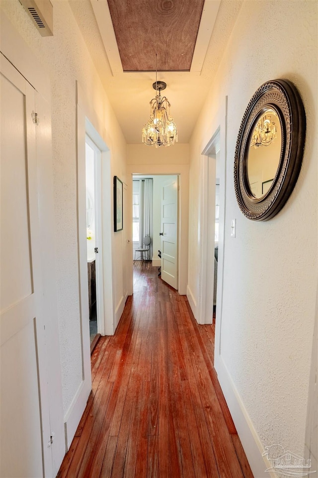 hallway with a notable chandelier and hardwood / wood-style flooring