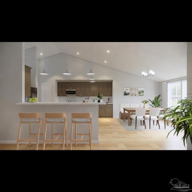 kitchen with high vaulted ceiling, an inviting chandelier, a kitchen breakfast bar, light hardwood / wood-style floors, and stainless steel appliances