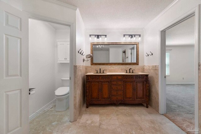 2960 Laurel Dr, Gulf Breeze, FL 32563 - full bathroom featuring tile walls, ornamental molding, a textured ceiling, double vanity, and toilet