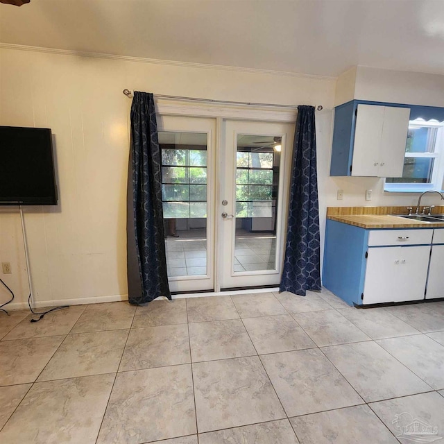 interior space featuring crown molding, sink, and light tile patterned floors