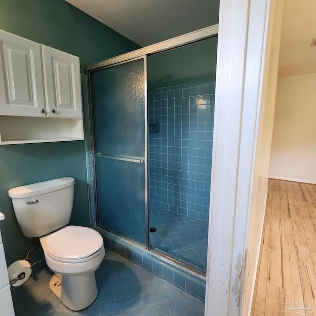 bathroom featuring toilet, hardwood / wood-style flooring, and a shower with shower door