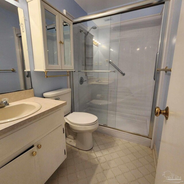 bathroom featuring a shower with shower door, toilet, and vanity