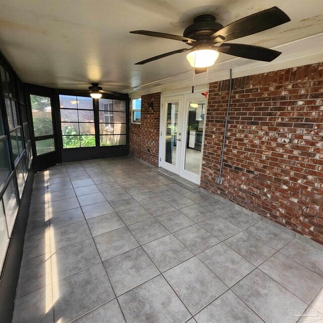 unfurnished sunroom featuring ceiling fan and french doors