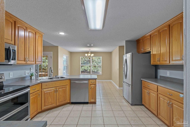 6299 Anderson Ln, Milton, FL 32570 - kitchen with appliances with stainless steel finishes, a textured ceiling, a peninsula, a chandelier, and light tile patterned flooring