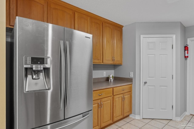 6299 Anderson Ln, Milton, FL 32570 - kitchen with stainless steel fridge with ice dispenser, light tile patterned flooring, brown cabinets, and light countertops