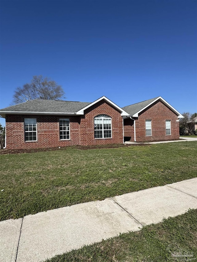 ranch-style house with brick siding, a front yard, and a shingled roof